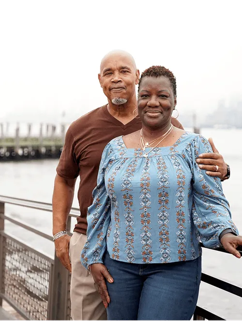 middle aged couple  standing in an outdoor pathway with a body of water in the background