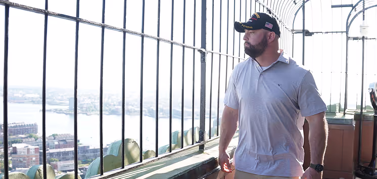 veteran male walking on a rooftop balcony looking out in the view